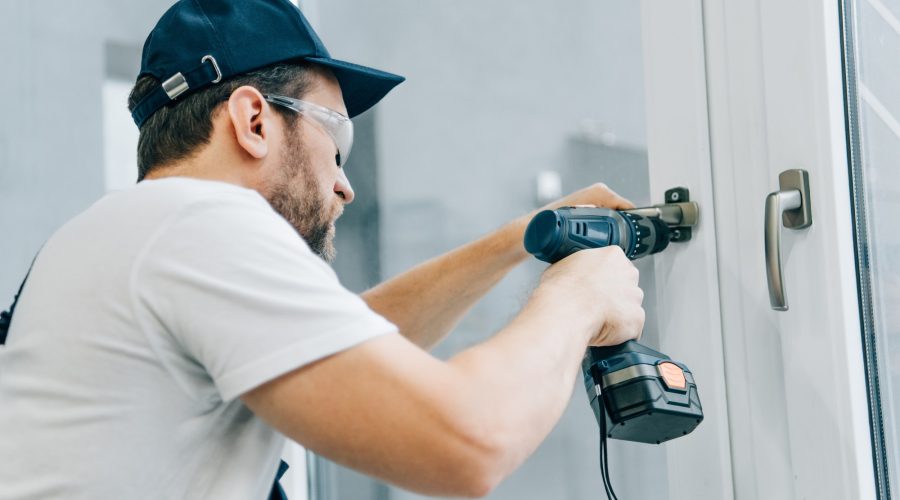 handyman-in-goggles-fixing-window-handle-by-electric-drill.jpg